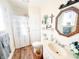 Bright bathroom with modern vanity, decorative mirror, shower, and wood-look flooring at 327 Maxwell Rd, Indianapolis, IN 46217