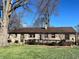 Charming home exterior with stone facade, wooden deck, and mature trees in a sunny setting at 327 Maxwell Rd, Indianapolis, IN 46217