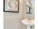 Elegant powder room showcasing a sleek pedestal sink, complemented by tasteful artwork and a modern mirror at 3745 Cantebury Dr, Franklin, IN 46131