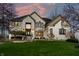 Elegant white brick home featuring well-kept lawn, black trim windows, and a dramatic sunset backdrop at 4243 Riverbirch Run, Zionsville, IN 46077