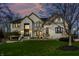Two-story white brick home, features lush green lawn, black trim windows, and dusk lighting at 4243 Riverbirch Run, Zionsville, IN 46077