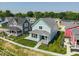 Light-blue home with lush green lawn and adjacent colorful houses, set against a wooded backdrop at 5421 Upper Garden Way, Zionsville, IN 46077