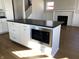 Kitchen island with built-in microwave and black countertop in an open-concept space at 5421 Upper Garden Way, Zionsville, IN 46077