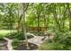 Lush backyard showcasing a private wooded area with stone paths, a seating area, and mature trees at 5977 S 800 E, Zionsville, IN 46077