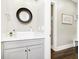 Stylish half bathroom with modern fixtures, sleek vanity, and decorative round mirror at 6208 W Foster Ridge Ln, Pendleton, IN 46064