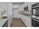 Modern kitchen with stainless steel appliances, white cabinetry, light countertops, and hardwood flooring at 7070 Nine Penny Dr, Brownsburg, IN 46112