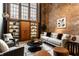 Cozy living room with exposed brick wall, neutral-colored furnishings, and natural light from large windows at 735 Lexington Ave # 1, Indianapolis, IN 46203