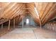 Spacious unfinished attic with exposed wood beams and a window, offering potential for customization and storage at 7472 Windridge Way, Brownsburg, IN 46112
