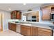 Traditional-style kitchen features wood cabinets, gray countertops, and view to living room with fireplace at 7472 Windridge Way, Brownsburg, IN 46112