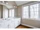 Bathroom with double sinks, white cabinets, and a view from the window at 8001 N Illinois St, Indianapolis, IN 46260