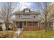 Charming two-story home featuring a covered porch and mature trees in a well-maintained front yard at 825 N Bancroft St, Indianapolis, IN 46201