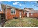 Backyard view of brick home with a small lawn and patio area, featuring a detached garage and exterior access door at 959 E Bradbury Ave, Indianapolis, IN 46203