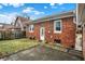 Brick home exterior featuring a small patio, grassy yard, and a white back door for easy access at 959 E Bradbury Ave, Indianapolis, IN 46203