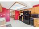 Eat-in kitchen with wood cabinets, black appliances, a skylight, and red accent walls at 10709 E County Road 100 N, Indianapolis, IN 46234