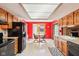 A wide view of the eat-in kitchen with skylight, showing wood cabinets, black appliances, and a table set for two at 10709 E County Road 100 N, Indianapolis, IN 46234