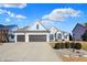 Charming brick home with a well-manicured lawn and a three-car garage, enhanced by a blue sky filled with fluffy clouds at 10896 Fairwoods Dr, Fishers, IN 46037