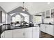 Open kitchen with white cabinets, wood floors, dark countertops, and stainless steel appliances, perfect for cooking and entertaining at 10896 Fairwoods Dr, Fishers, IN 46037