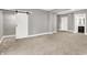 Expansive basement space with neutral carpet and gray walls, featuring a barn door and an access to a bathroom at 14474 Treasure Creek Ln, Fishers, IN 46038