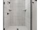 Modern shower with white tile, a black shower head, and glass doors and featuring tiled corner shelves at 15675 Woodford Dr, Westfield, IN 46074