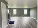 Open living room with hardwood floors, gray walls, and lots of natural light from the three windows at 215 Traditions Pass, Greenwood, IN 46143