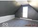 A quiet attic space with neutral color walls, a window, and carpet flooring at 711 W Centennial Ave, Muncie, IN 47303