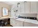 Bright laundry room with a utility sink, washer, dryer, storage cabinets, and wallpapered accent wall at 11850 Deer Walk Dr, Cicero, IN 46034