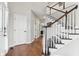 Inviting entryway with hardwood floors and an elegant staircase featuring white spindles and stained handrail at 14466 Integrity Ct, Carmel, IN 46033