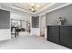 Open concept space, showcasing wall paneling, modern chandelier, and carpeted floors with access to home office at 14466 Integrity Ct, Carmel, IN 46033