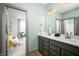 Bright bathroom with double vanity, gray cabinets and a view into the adjoining bedroom at 15871 Vitalize Run, Fishers, IN 46040
