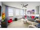 Bright bonus room with gray sofa, red accents, ceiling fan and ample natural light at 15871 Vitalize Run, Fishers, IN 46040