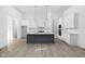 Bright kitchen featuring white cabinets, gray island, modern lighting, and hardwood flooring at 17364 Pinellas Ave, Westfield, IN 46074