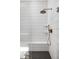 Modern shower showcasing white vertical tiles, a bronze shower head, and a black-tiled floor at 17364 Pinellas Ave, Westfield, IN 46074