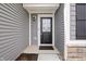 Charming front entrance showcases gray siding, a black front door, and clean landscaping at 19568 Astoria Ave, Sheridan, IN 46069