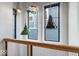 Hallway featuring modern pendant lighting, wood railings, and views of the neighborhood through several windows at 2026 Alvord St, Indianapolis, IN 46202