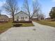 Charming exterior view of home with gravel driveway, large trees, and attractive landscaping at 208 S Conger St, , IN 47272