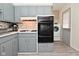 Bright kitchen featuring gray cabinets and a mosaic backsplash, modern appliances, and wood-look vinyl flooring at 243 S 3Rd Ave, Beech Grove, IN 46107