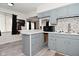 This kitchen features gray cabinets, breakfast bar, modern appliances, and wood-look vinyl flooring at 243 S 3Rd Ave, Beech Grove, IN 46107
