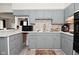 This kitchen features gray cabinets, mosaic tile backsplash, modern appliances, and wood-look vinyl flooring at 243 S 3Rd Ave, Beech Grove, IN 46107