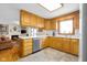 Well-lit kitchen with wooden cabinets, stainless steel dishwasher, and seamless view to the living room at 2665 Chestnut St, Columbus, IN 47201