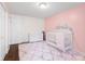 Bedroom featuring a white crib, changing table, and pink accent wall, creating a cozy and inviting space at 3232 Beech Dr, Columbus, IN 47203