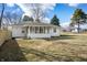 Back exterior view shows sunroom addition and level yard with wooden privacy fence to the left at 3626 St. Charles St, Anderson, IN 46013