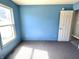 Bedroom with blue painted walls, carpet flooring, a window letting in natural light, and a white door at 4619 Carrollton Ave, Indianapolis, IN 46205
