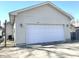 A detached single-car garage features a white door and exterior lights on each side, with the house number 