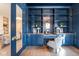 Chic blue home office with custom shelves, desk, and a modern glass-door entryway at 5537 Broadway St, Indianapolis, IN 46220