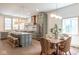 An eat-in kitchen with light-green cabinets, marble countertops, and stainless appliances adjoins a dining area with rattan chairs at 5537 Broadway St, Indianapolis, IN 46220