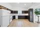 Bright kitchen features dark cabinetry, white appliances and countertop, with light wood flooring at 602 Tuscany Trl, Lapel, IN 46051