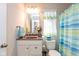 A neat bathroom includes a single sink vanity with a mirror, a toilet, and a shower with a decorative curtain at 6400 Woodland Ln, McCordsville, IN 46055
