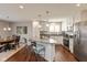 Well-lit kitchen with stainless steel appliances, granite countertops, island with seating, and hardwood floors at 6400 Woodland Ln, McCordsville, IN 46055