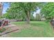 Large, grassy backyard with mature trees, a patio area, and a trampoline at 6616 W 15Th St, Indianapolis, IN 46214