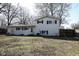 Exterior view of a home's backyard, featuring a grassy lawn, mature trees, and the back of the home at 6616 W 15Th St, Indianapolis, IN 46214